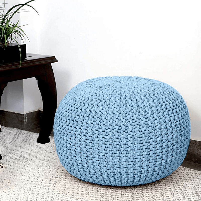 Stylish blue knitted ottoman in a cozy room, perfect for adding affordable comfort and elegance to your living space.