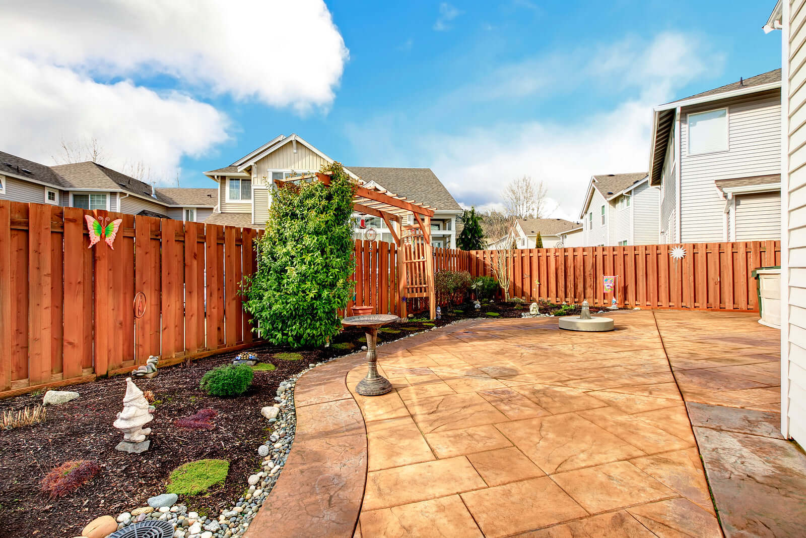 Stylish backyard with affordable garden decor including a birdbath, gnomes, and greenery, enhancing outdoor space on a budget.