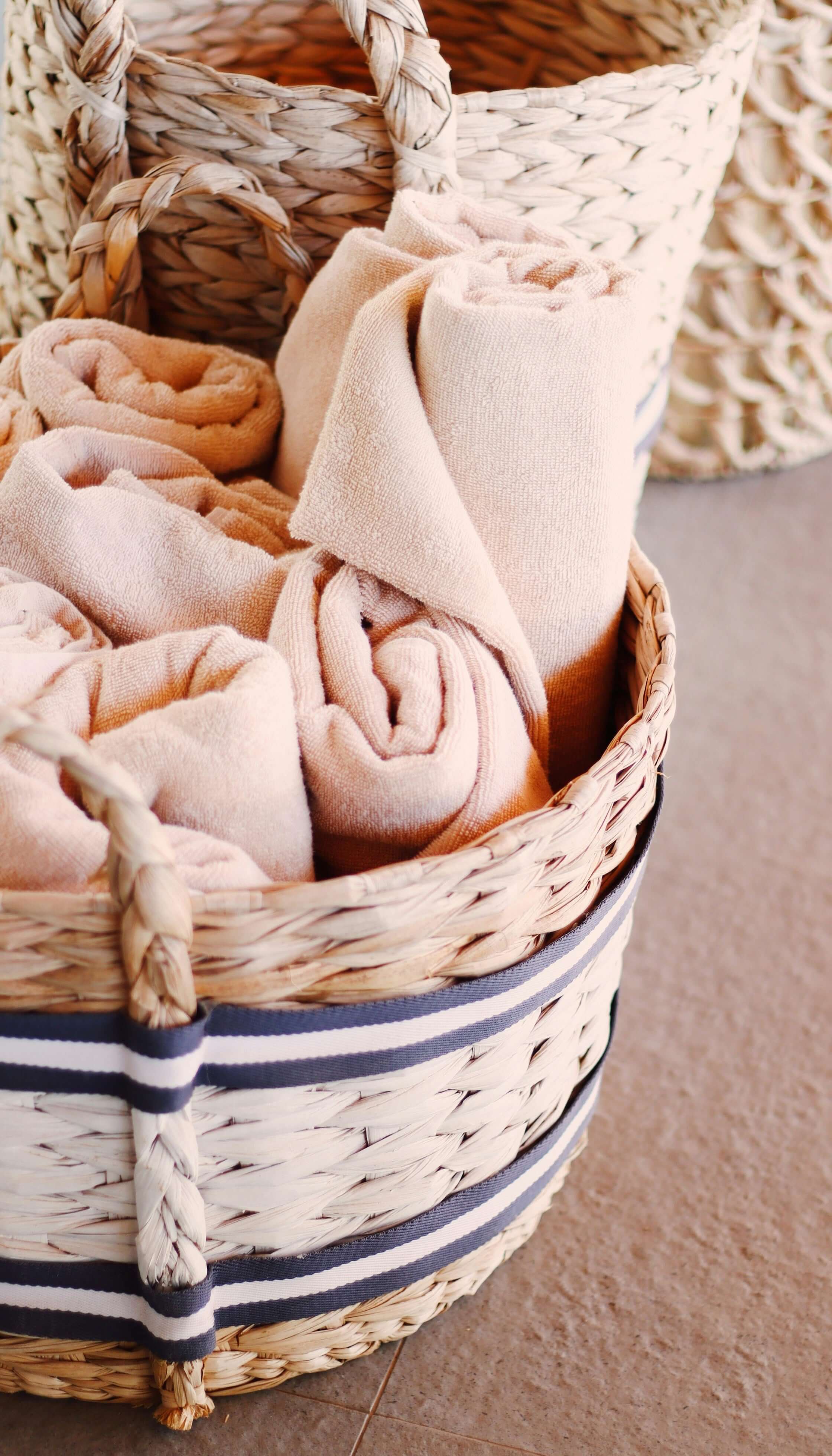 Luxurious beige towels in stylish woven basket, perfect for affordable bathroom décor on a budget.