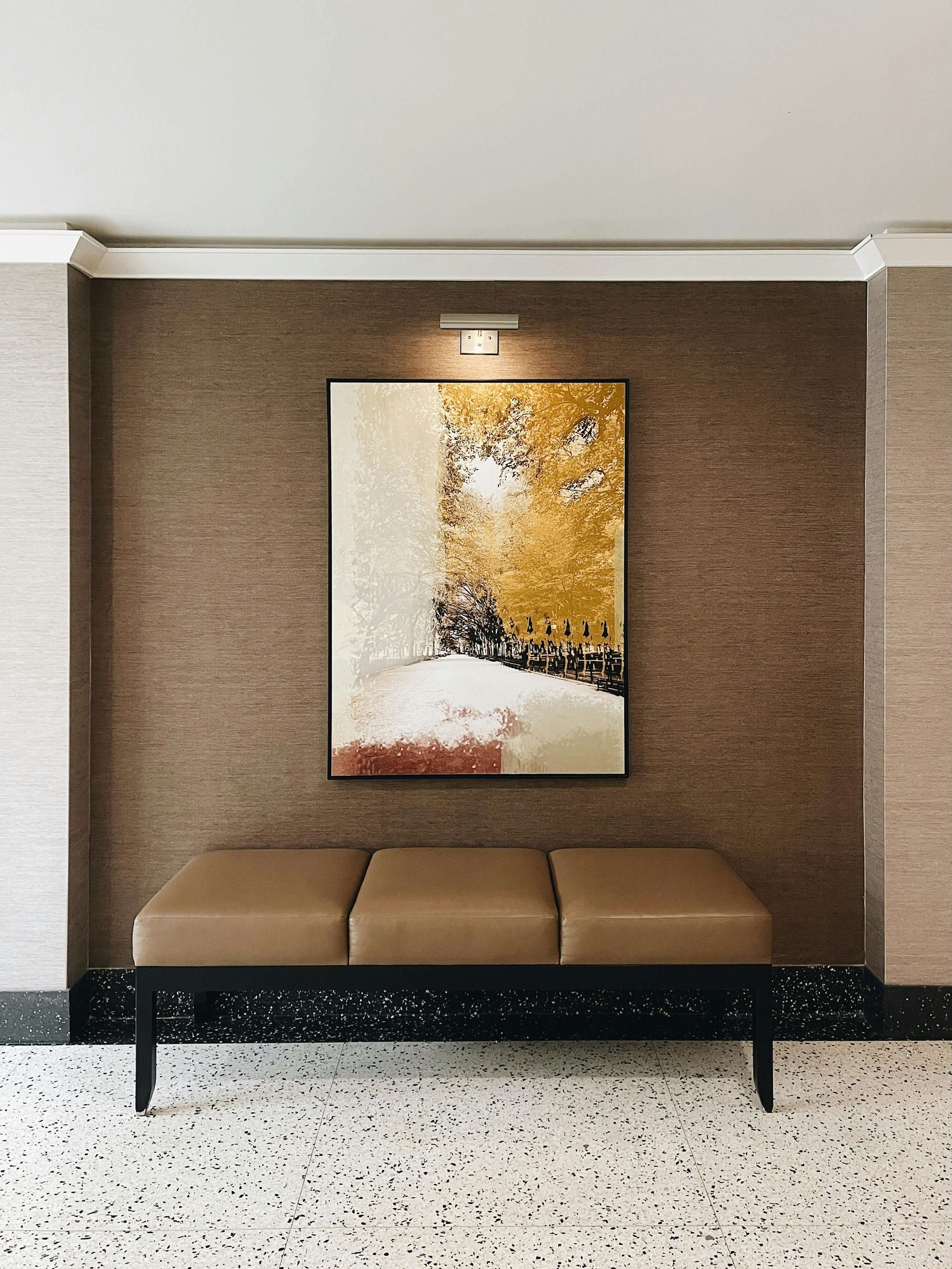 Modern lobby with an affordable landscape canvas above a brown bench. Quality artwork for budget-conscious décor.