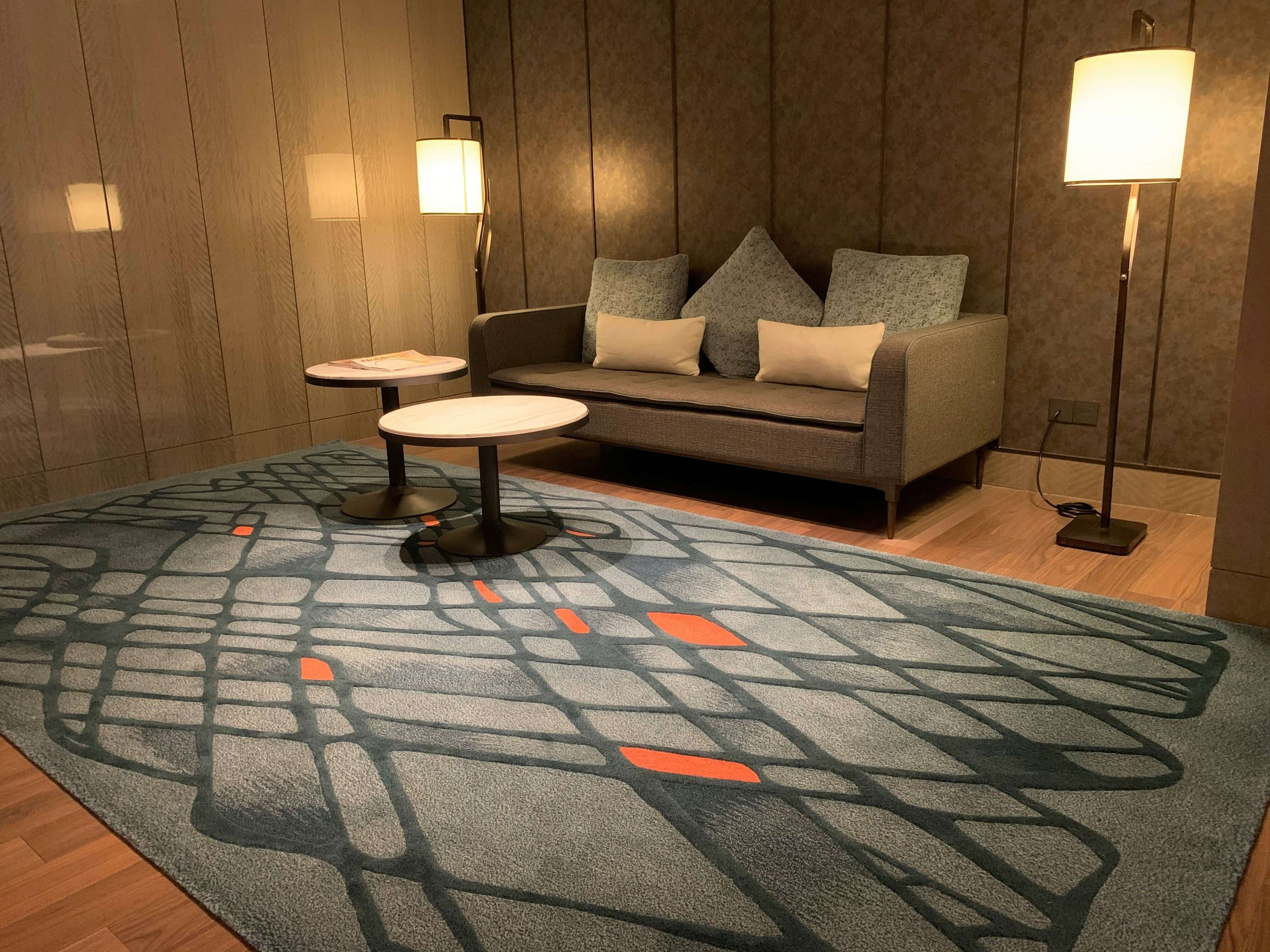 Modern living room featuring a stylish blue rug with abstract patterns, complementing a sleek grey sofa set, and warm lighting.