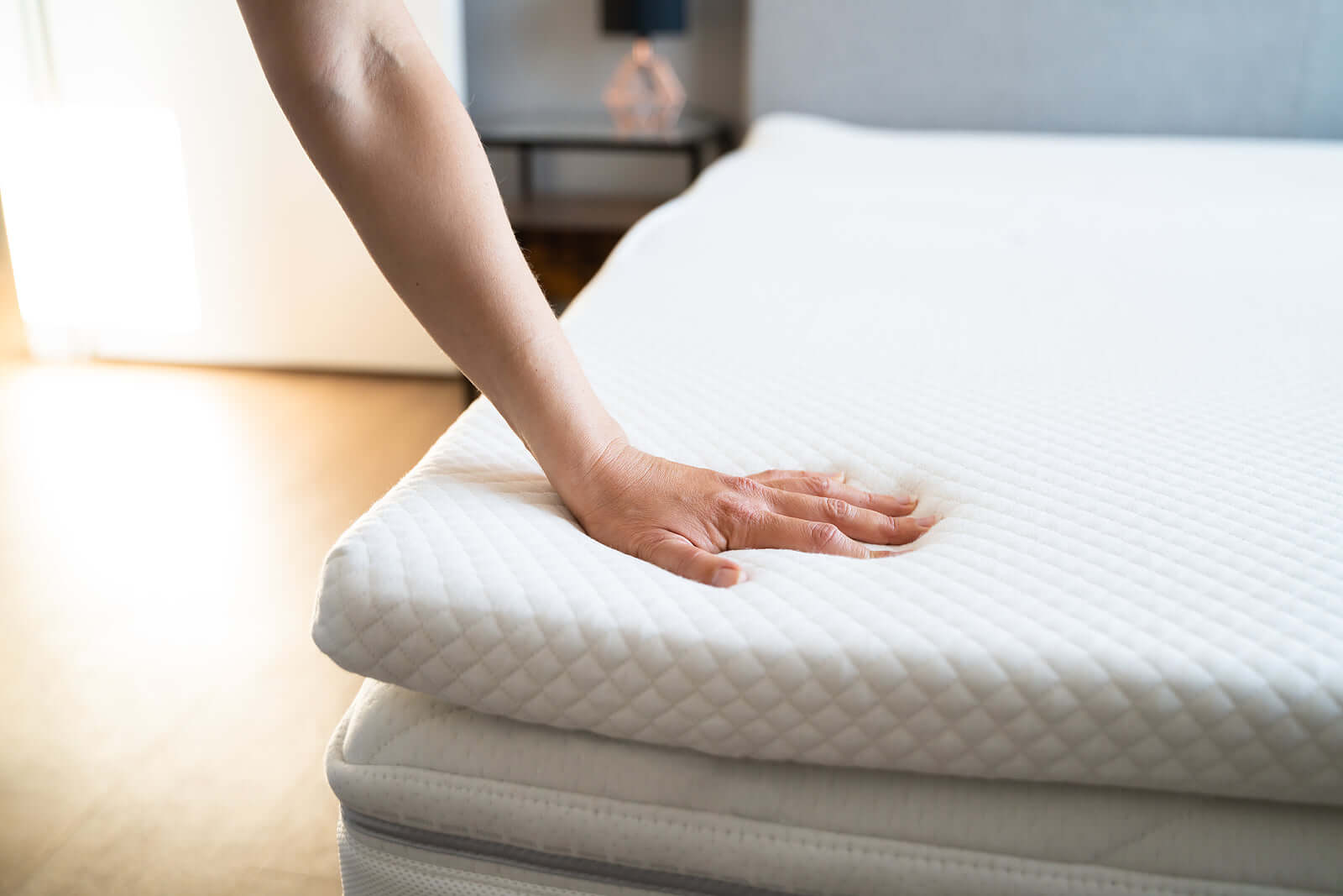 Hand pressing soft, affordable mattress topper showcasing quality comfort from S & D's Value Store.