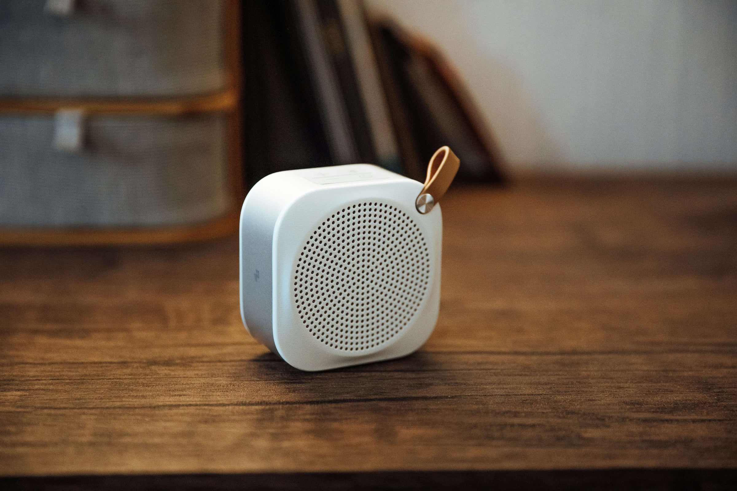 Compact white speaker on wooden table, showcasing affordable and quality tech essentials from S & D's Value Store.