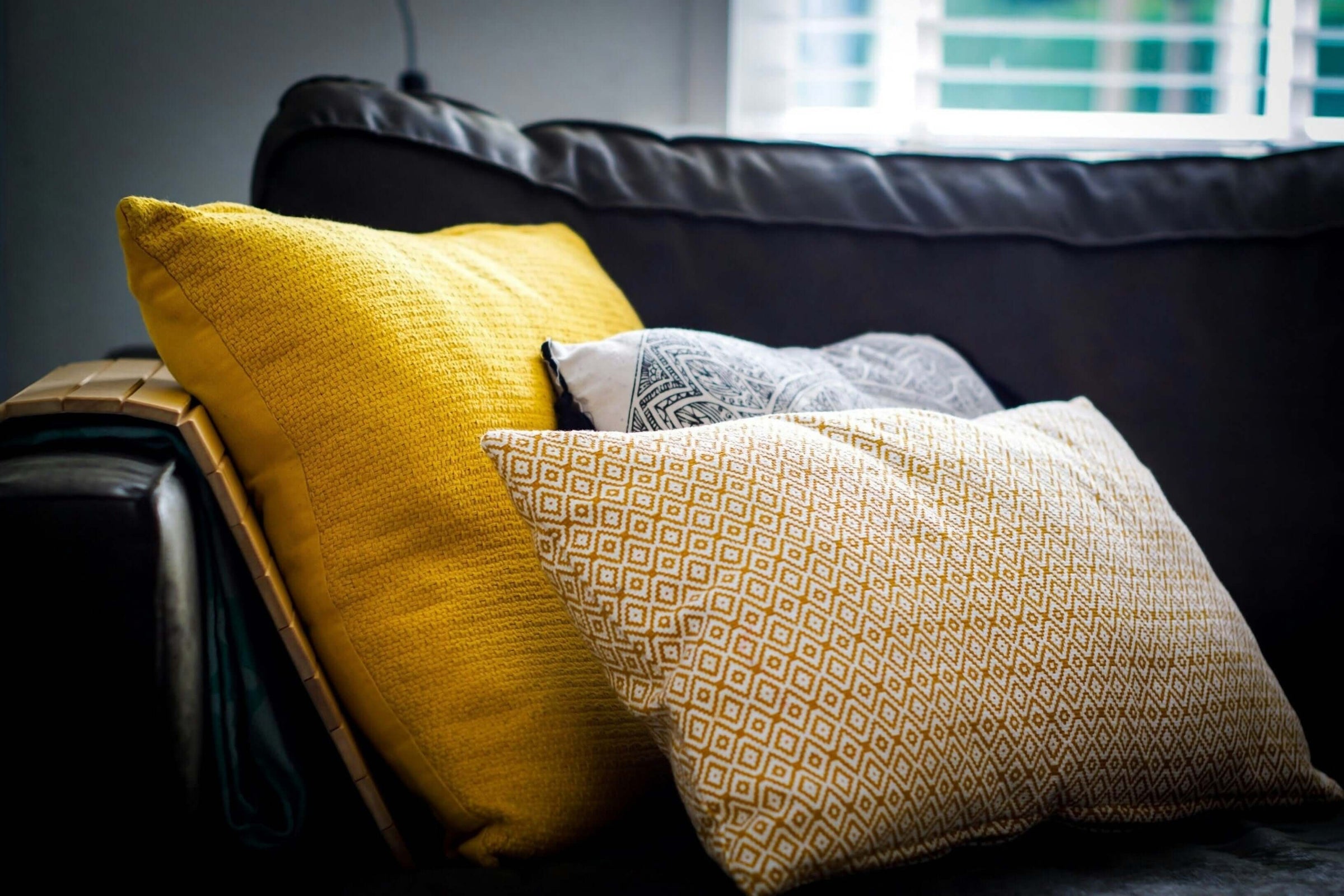 Stylish affordable cushions in vibrant yellow and patterned designs on a sofa, perfect for refreshing your space on a budget.