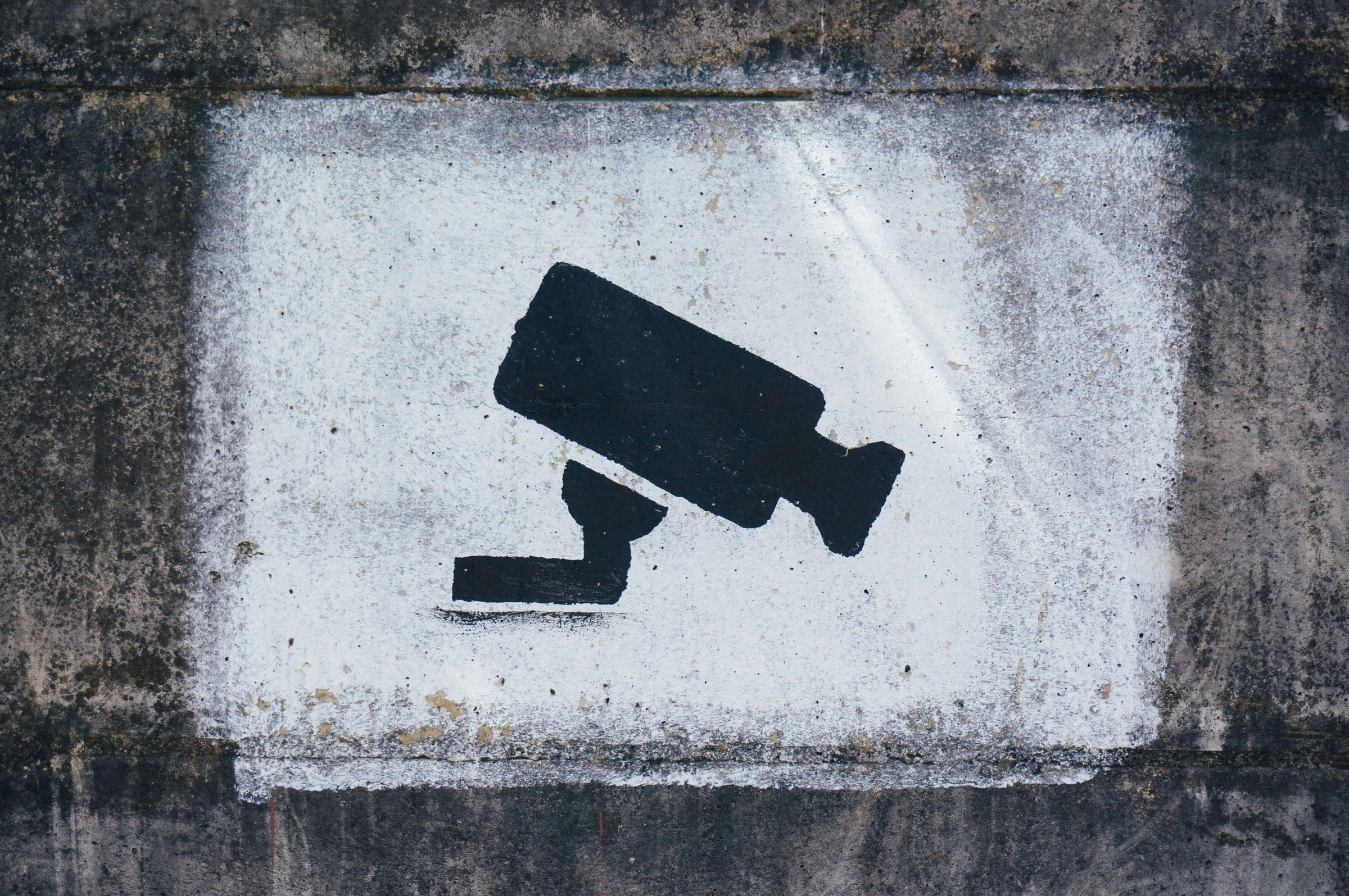 CCTV camera icon painted on a concrete wall, representing affordable and quality security solutions for home safety.