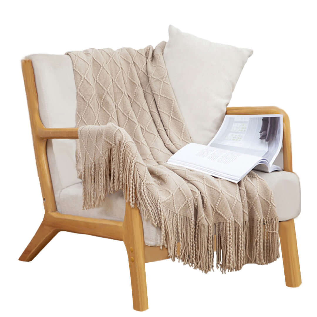 Affordable quality homewares - cozy beige armchair with a knitted throw and a magazine, showcasing value furniture.