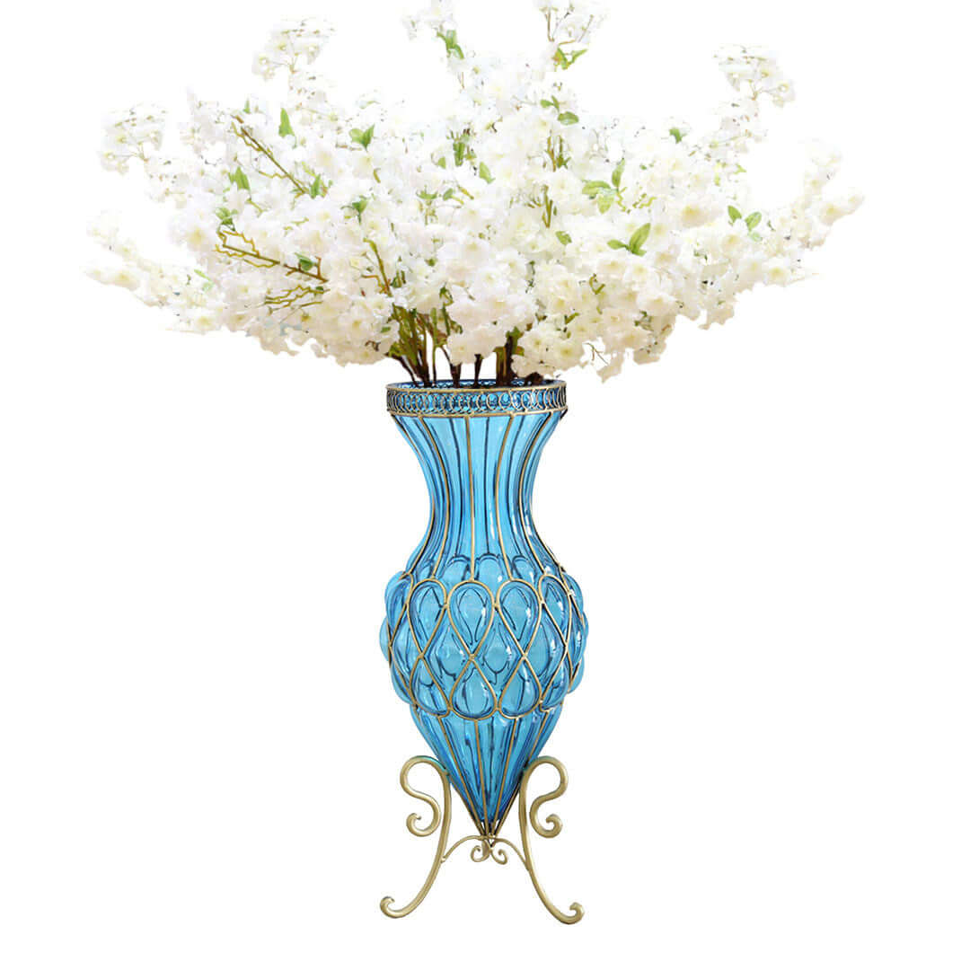 Elegant blue glass vase with ornate metal design, filled with white artificial flowers. Affordable homewares offering quality and value furniture.