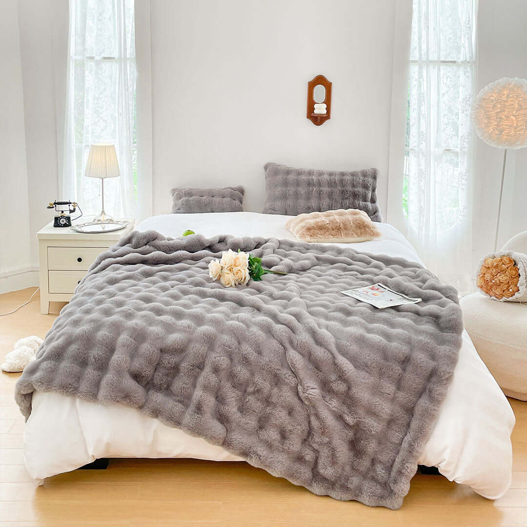 Cozy bedroom with grey textured blanket, stylish homewares, and comfortable furniture. Affordable quality value furniture and decor.