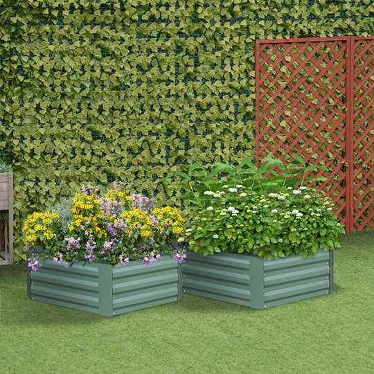 Raised garden beds with vibrant flowers and plants in a well-manicured backyard with a green ivy-covered wall and red trellis.