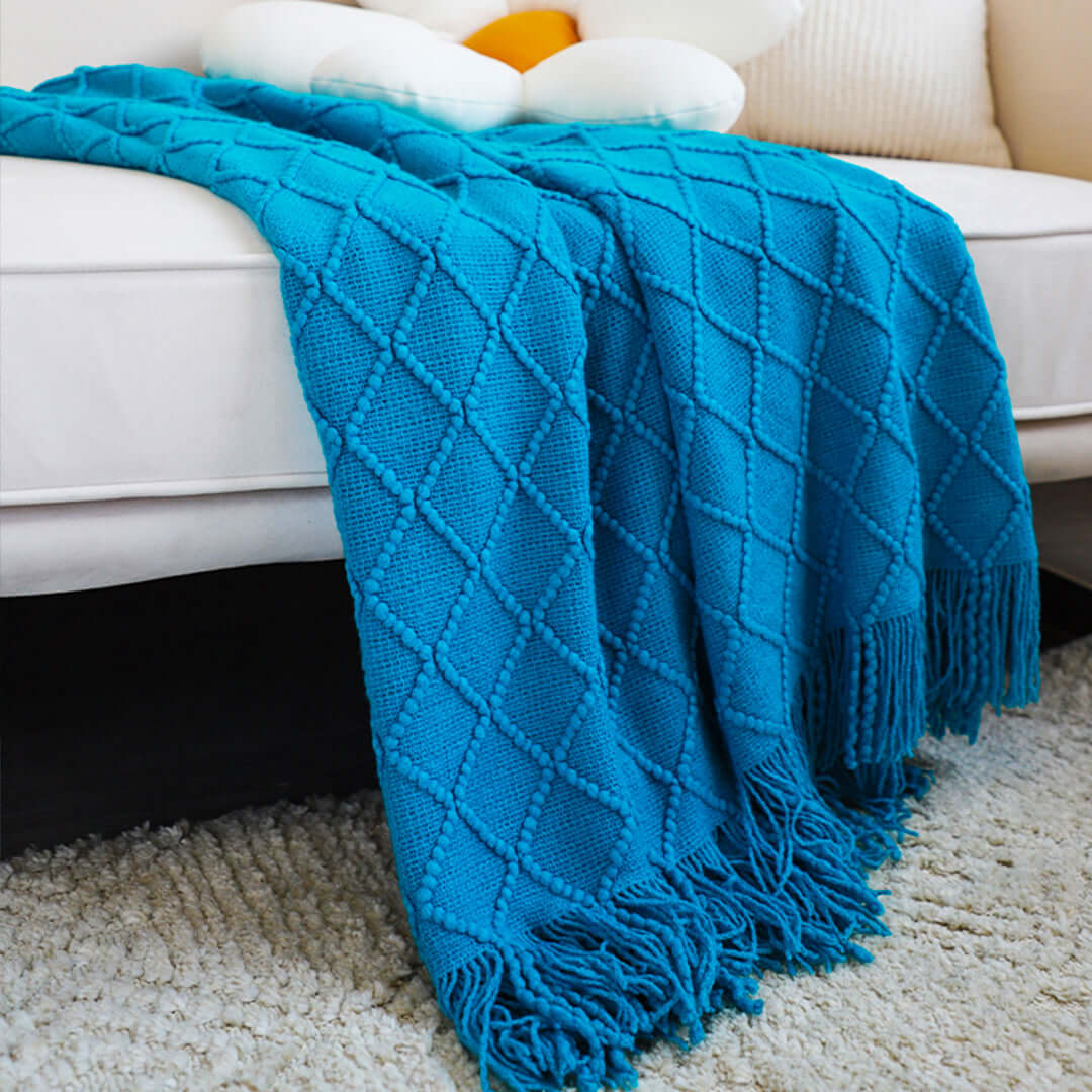 Affordable quality blue knitted throw blanket on a sofa, perfect value homeware addition for cozy living room decor.