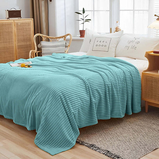 Affordable quality homewares featuring a turquoise throw blanket on a cozy, well-decorated bed with value furniture in a stylish bedroom.