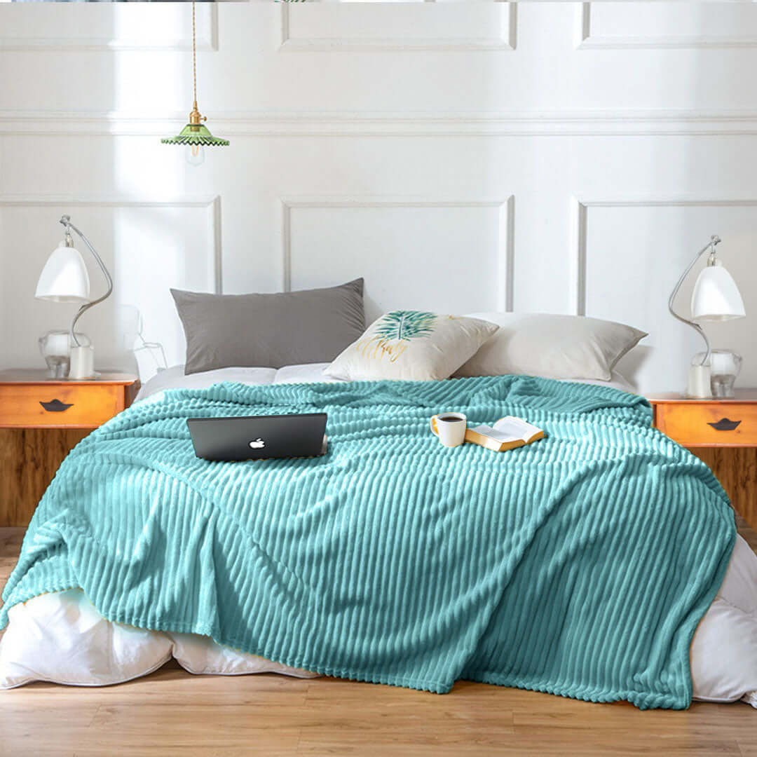 Affordable quality homewares - cozy bedroom setup with teal blanket, pillows, bedside tables, and value furniture elements.