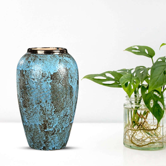 Stylish blue ceramic vase with intricate patterns next to a green potted plant, perfect for affordable quality homewares and value furniture.