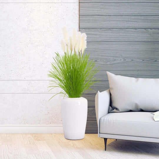 Affordable homewares - a white vase with tall green grass, placed beside a modern grey couch against a wooden wall backdrop