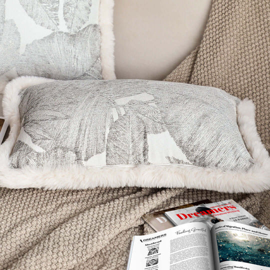 Decorative cushion on a cozy beige blanket with a home decor magazine. Affordable homewares, quality, value furniture.