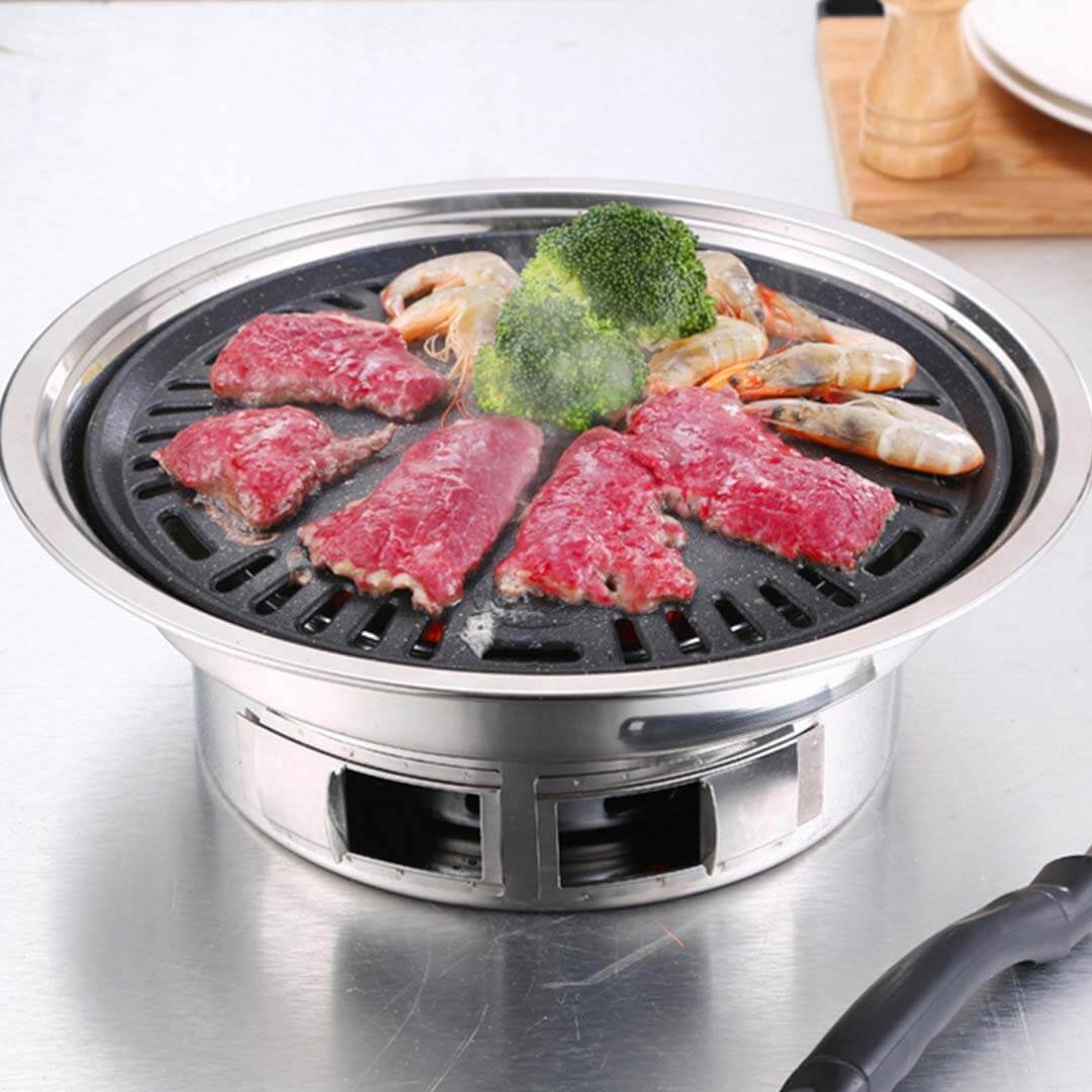 Stainless steel portable grill cooking steak, shrimp, and broccoli.