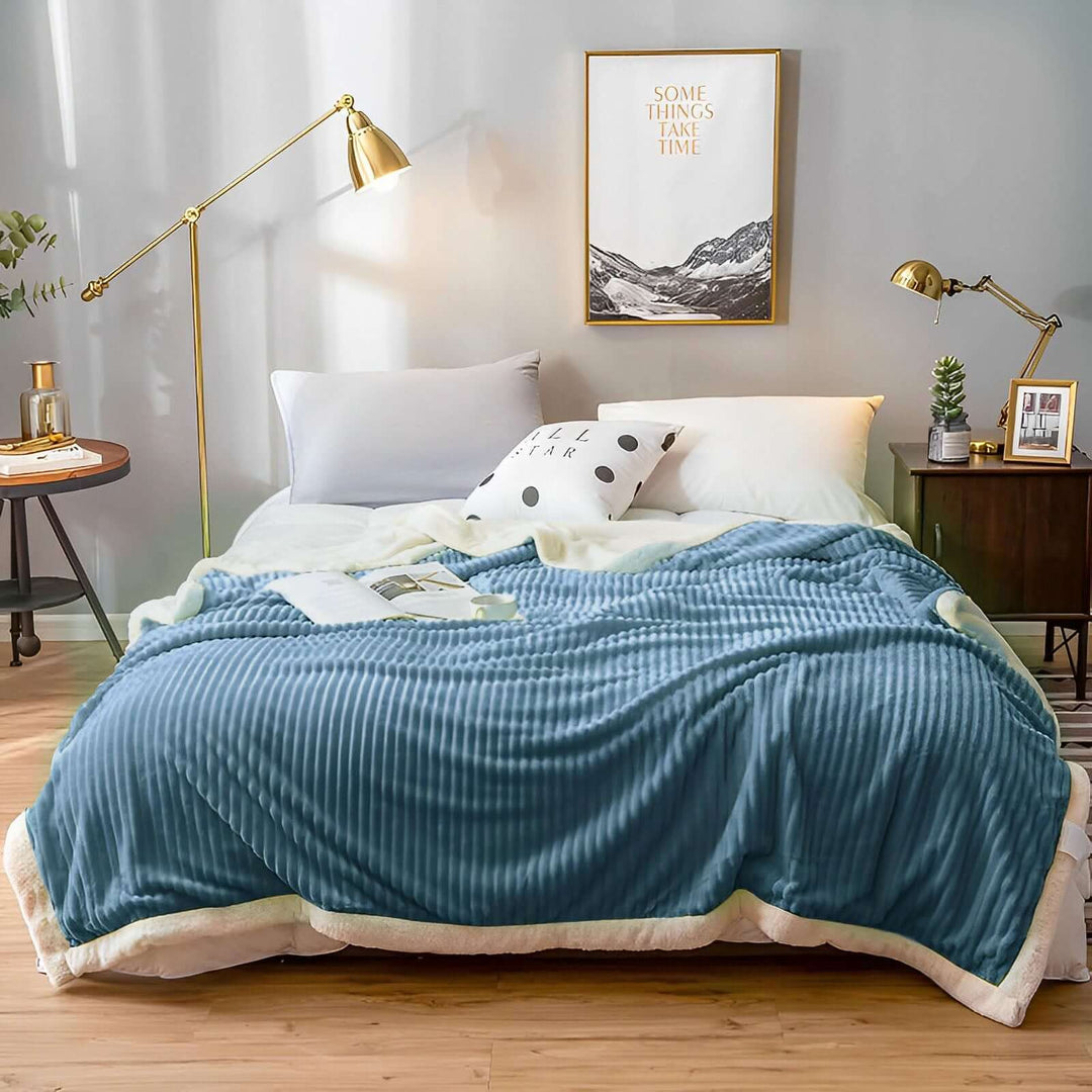 Cozy bedroom with a comfortable bed draped in a blue blanket, flanked by modern lamps and stylish home decor. Affordable value furniture. Quality homewares.