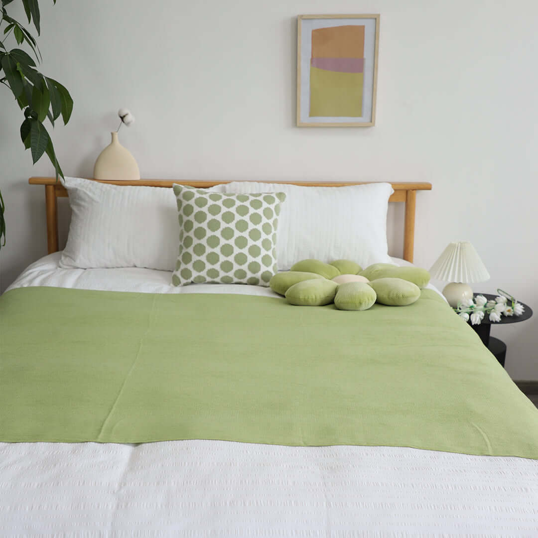 Cozy bedroom with green and white bedding, decorative pillows, framed art, and plants, showcasing affordable quality homewares and value furniture.