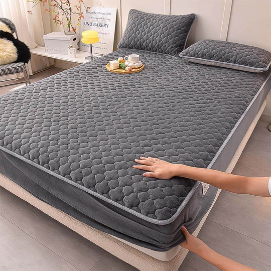 Affordable quality homeware featuring a value furniture gray quilted mattress topper and matching pillows in a cozy bedroom setting.