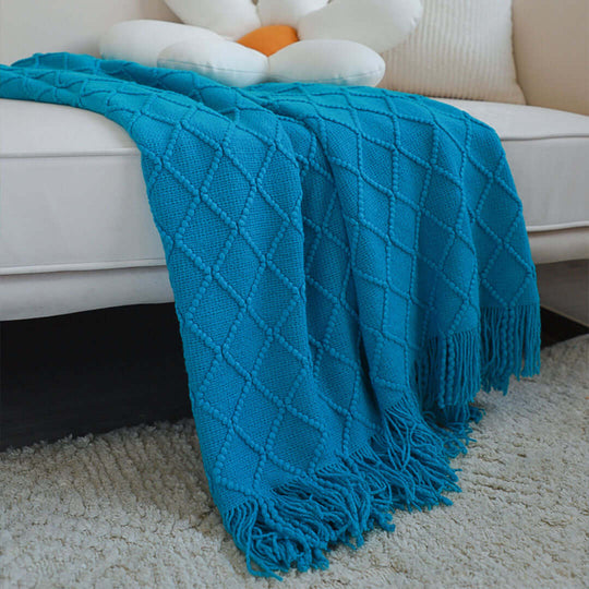 Affordable quality homewares - blue diamond-patterned throw blanket with fringe on a cream sofa, adding value to home furniture.