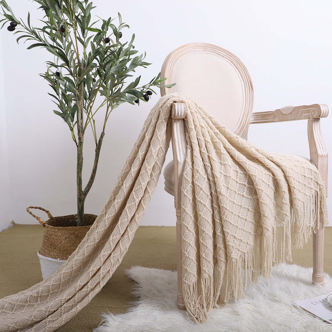 Affordable quality homewares - Elegant chair draped with a cozy beige blanket, potted plant, value furniture for stylish decor.