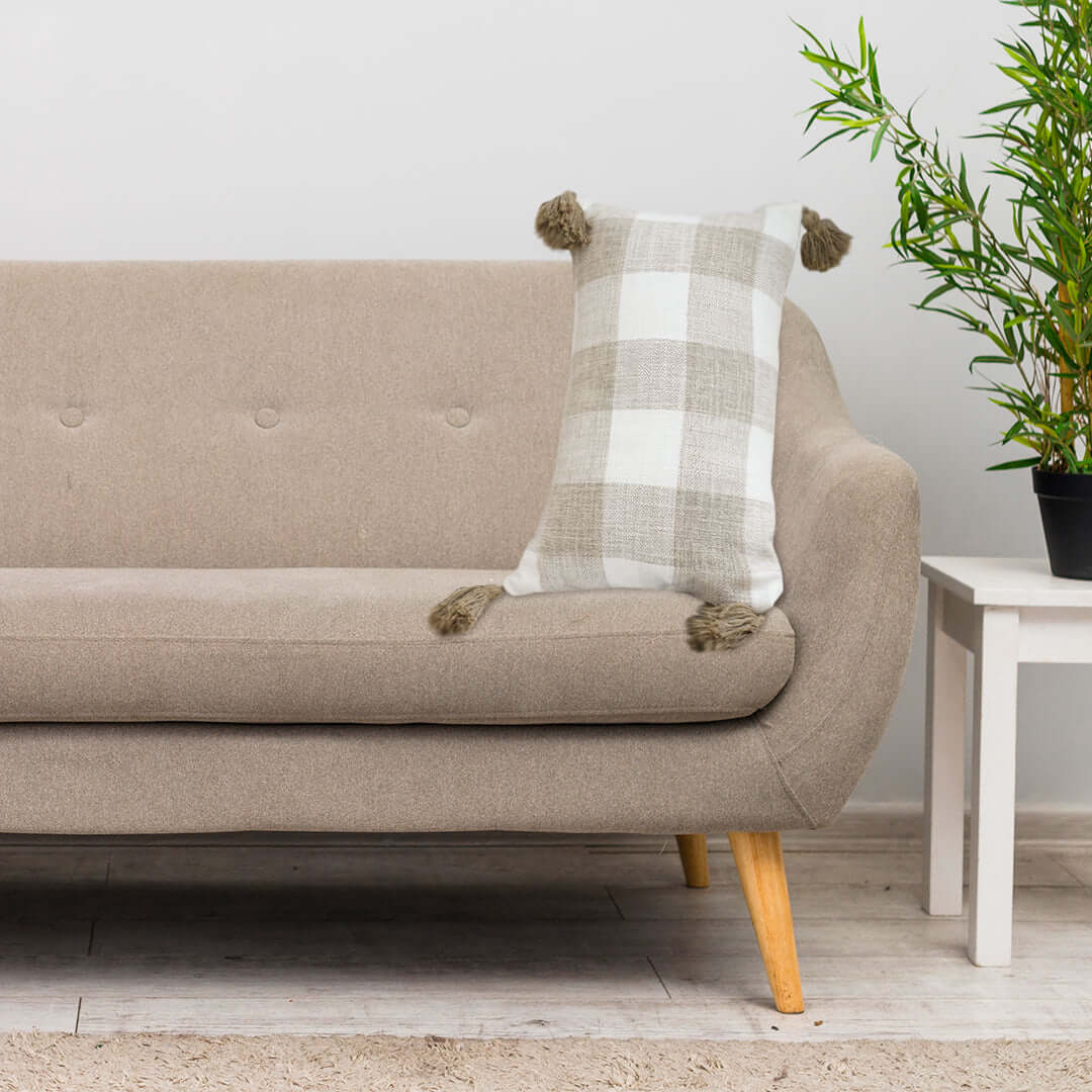 Affordable quality homewares - beige sofa with a checkered cushion and potted plant on end table, value furniture.