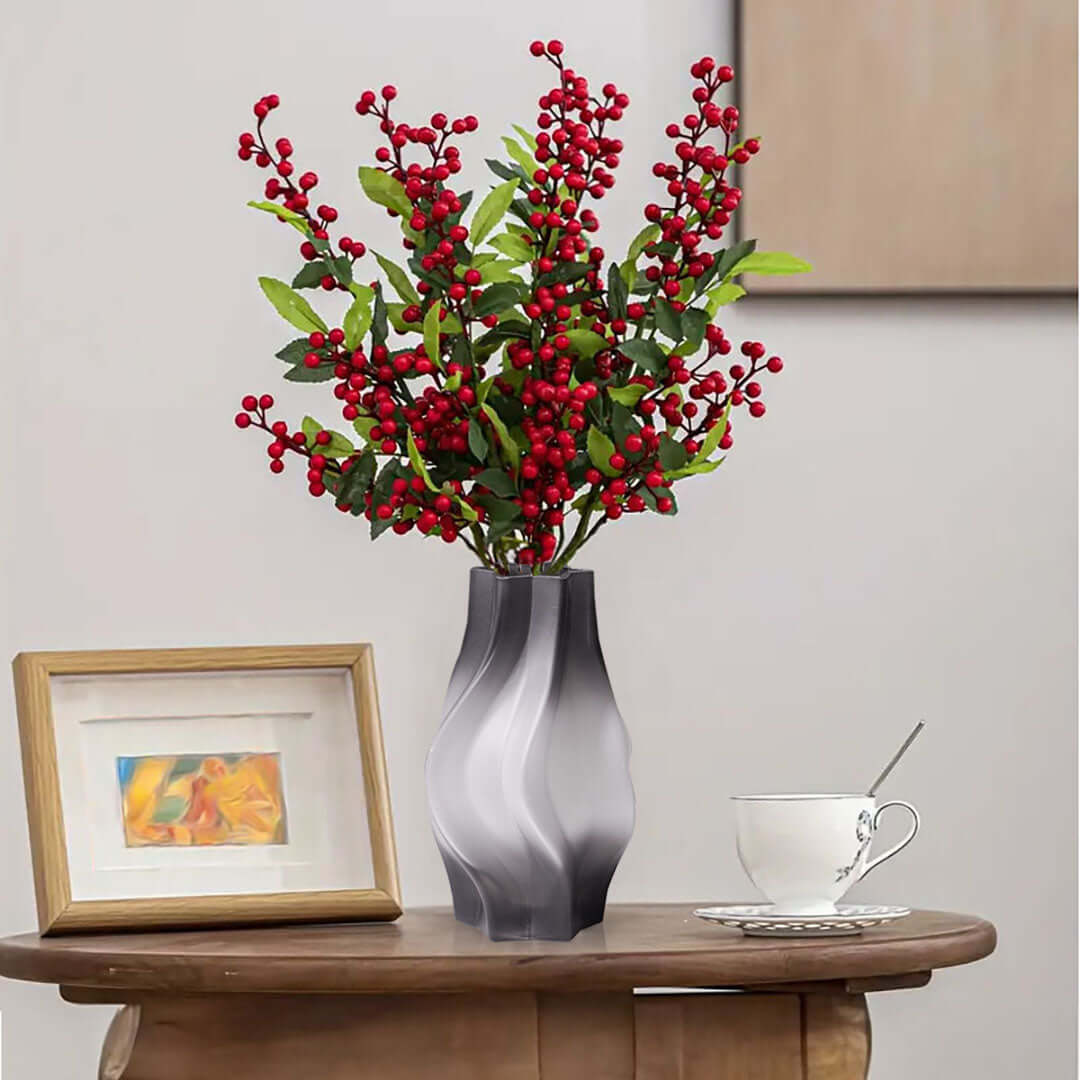 Stylish home decor with red berry vase on wooden table, accompanied by framed art and a cup and saucer, showcasing affordable quality homewares.