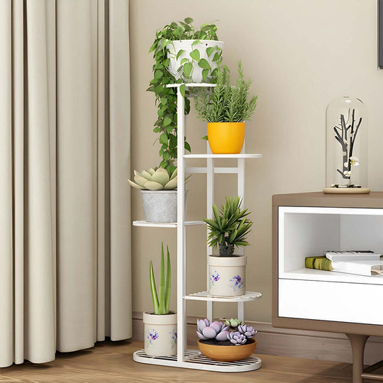 Affordable, quality homewares - stylish white plant stand with variety of potted plants next to value furniture in a living room.