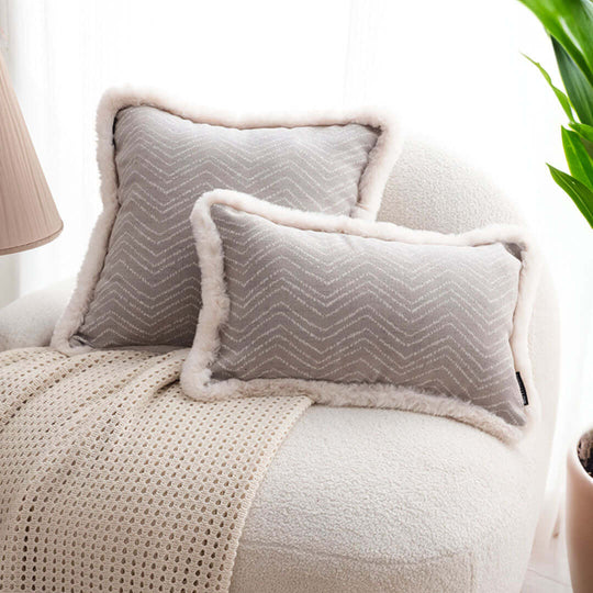 Affordable homewares - Quality value furniture - Cozy gray pillows with textured patterns on a beige chair, next to a plant and lamp.