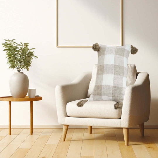 Affordable quality homewares and value furniture - stylish armchair with checkered pillow next to a minimalist side table with a potted plant.