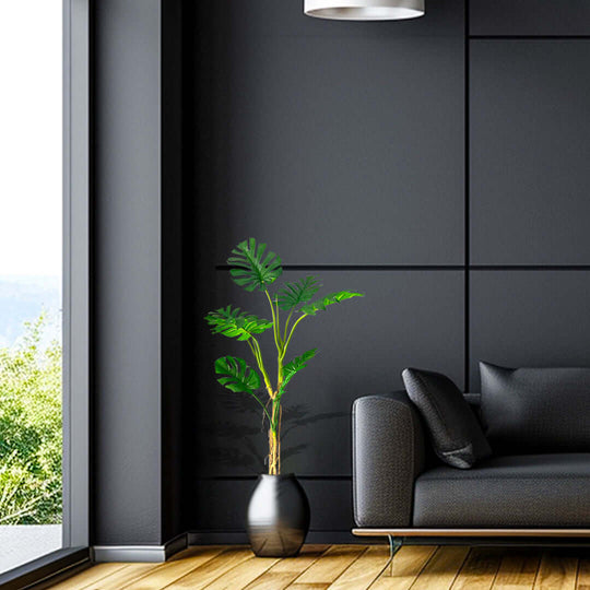 Modern living room with affordable quality value furniture and stylish homewares, featuring a sleek black sofa and green potted plant.