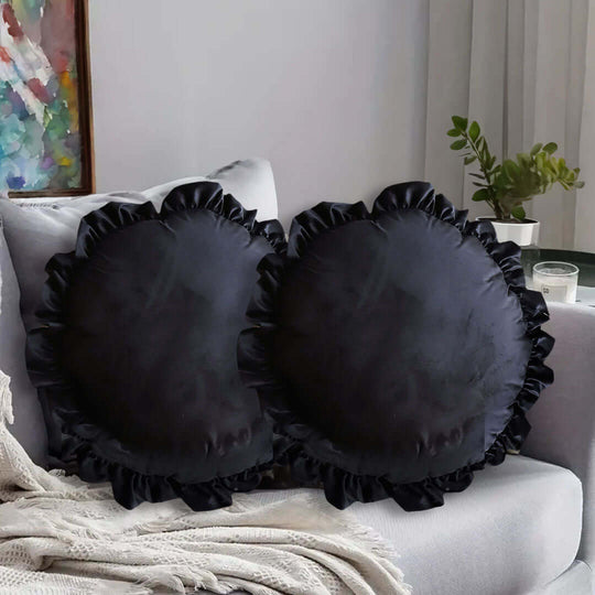 Affordable quality homewares and value furniture - set of two black decorative round pillows on a couch near a window.