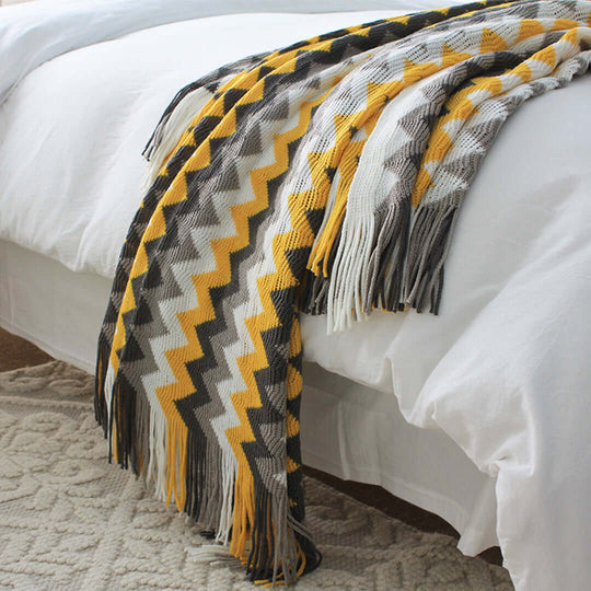 Affordable quality homewares with a yellow, white, and gray zigzag patterned blanket on a bed, showcasing value furniture.