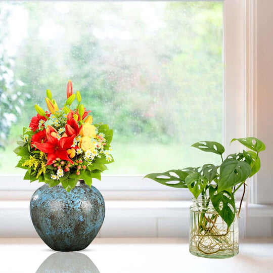 Vibrant floral bouquet in a rustic vase next to a green houseplant on a windowsill, showcasing affordable homewares and quality value furniture.