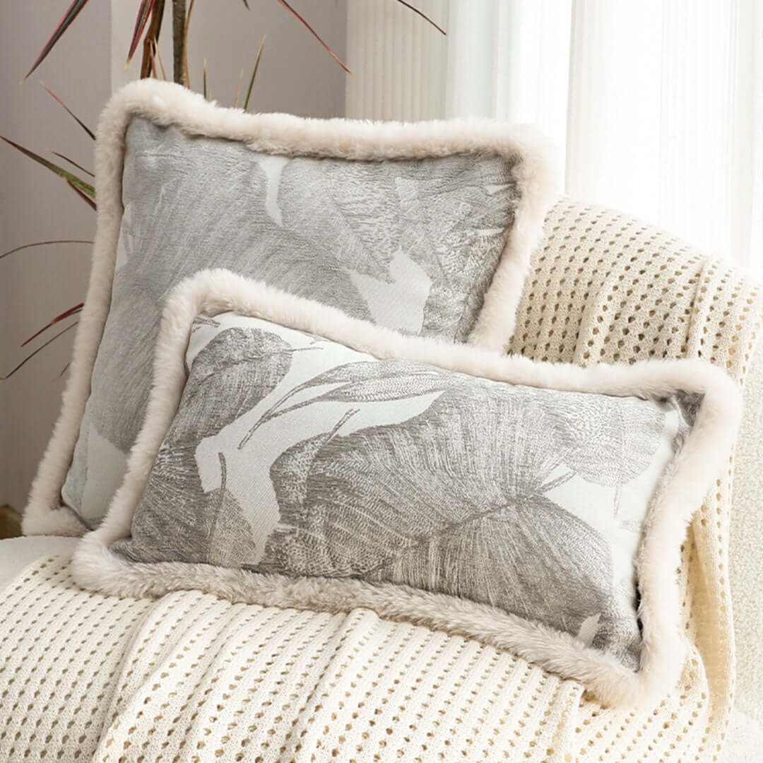 Affordable homewares - Quality throw pillows with grey abstract design and fur trim on cream knitted blanket for value furniture styling.