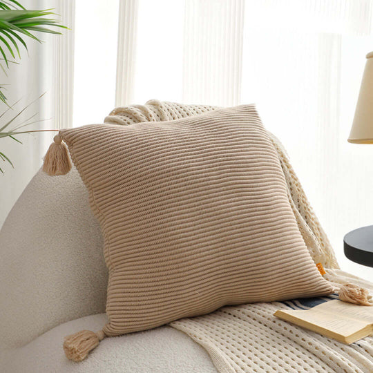 Cozy beige knitted throw pillow on a white armchair, adding a touch of affordable, quality homewares and value furniture to the living room.