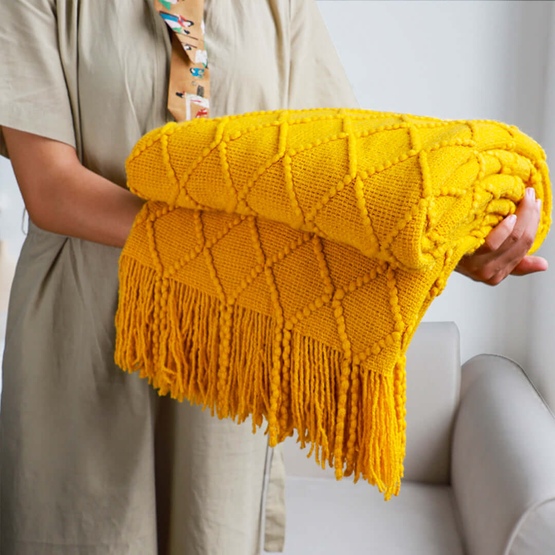 Person holding a vibrant yellow textured throw blanket with fringe, showcasing affordable and quality homewares and value furniture accents.