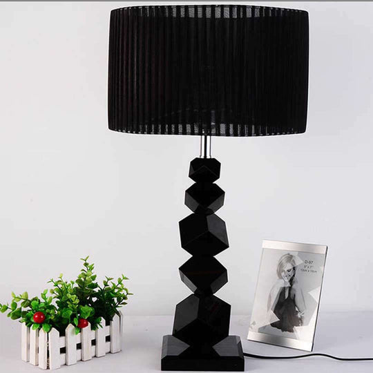 Modern black table lamp with geometric base next to small plant and framed photo, showcasing affordable and quality homewares and value furniture.