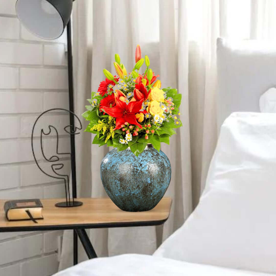 Vibrant flower arrangement in a rustic blue vase on a bedside table, enhancing affordable homewares with quality and value furniture.