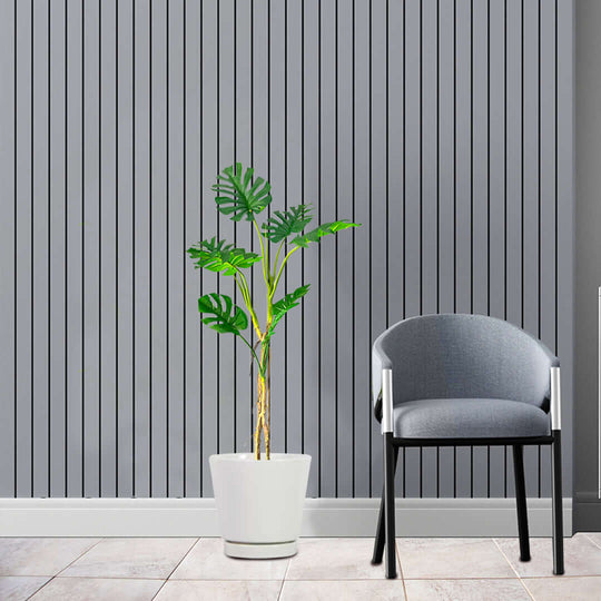 Affordable homewares: Quality potted plant and value furniture chair against modern vertical slat wall background.