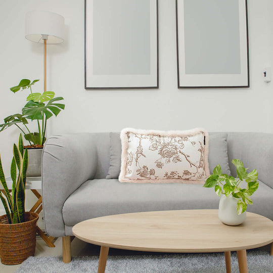 Affordable quality homewares and value furniture in a cozy living room with a grey sofa, decorative pillow, wooden coffee table, and indoor plants.