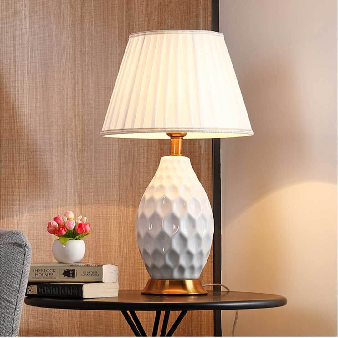 Stylish table lamp with textured base and white shade on a side table with books and decorative vase. Affordable quality homewares.