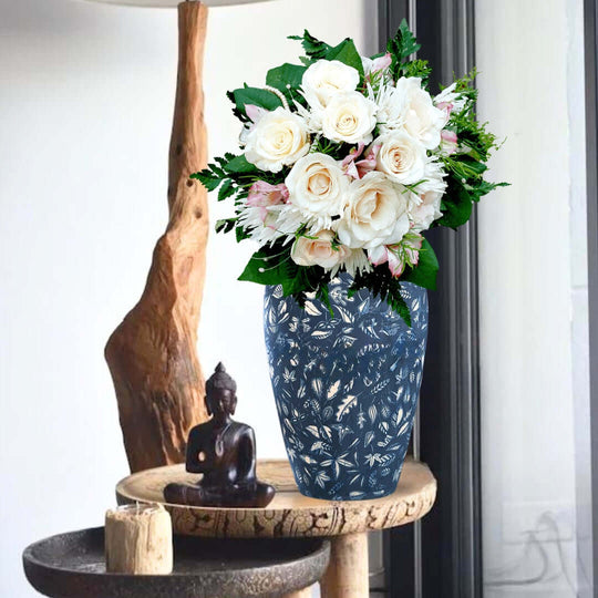 Elegant flower arrangement in a blue decorative vase with statue and rustic decor in a stylish home interior.