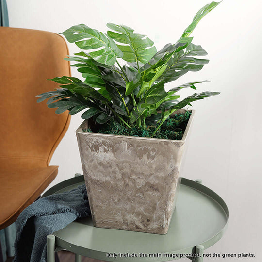 Modern stone-look planter on green side table with chair in background