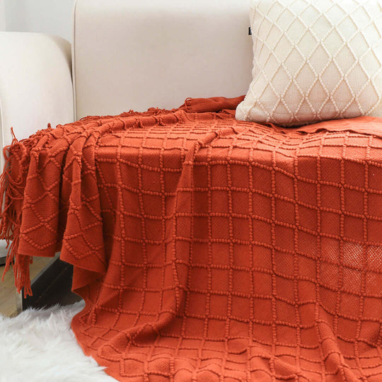 Affordable quality homeware with an orange throw blanket and cream pillow on a value furniture sofa.