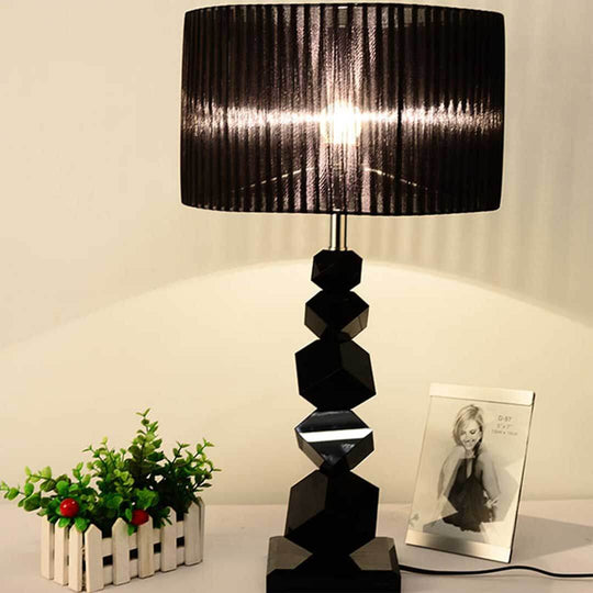 Modern black geometric table lamp next to a small plant and picture frame, offering affordable quality homewares and value furniture decor.