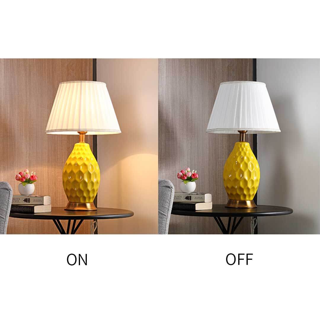 Yellow table lamp with white shade shown in both on and off states on a bedside table with flowers and books. Affordable quality homewares.