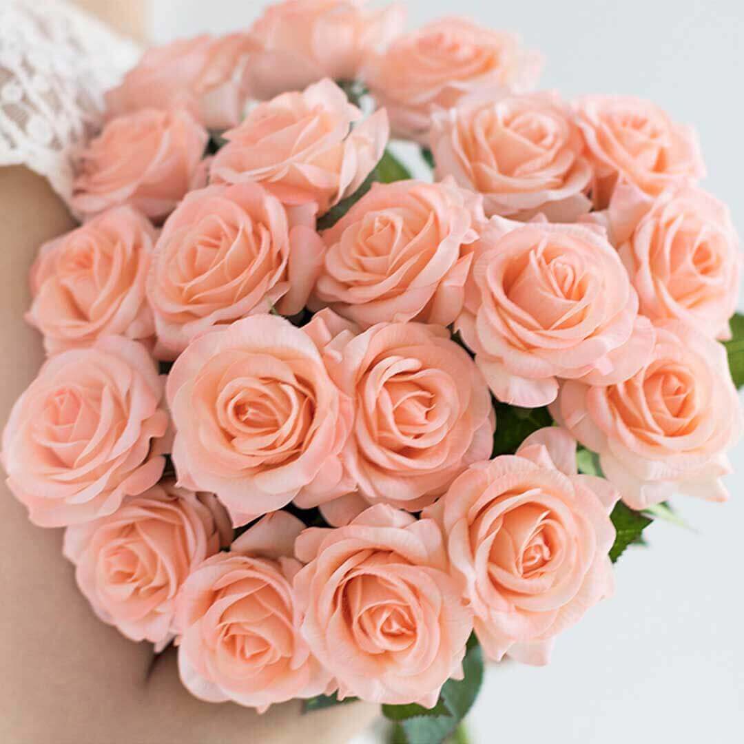 Bouquet of delicate peach roses held by a person in lace attire