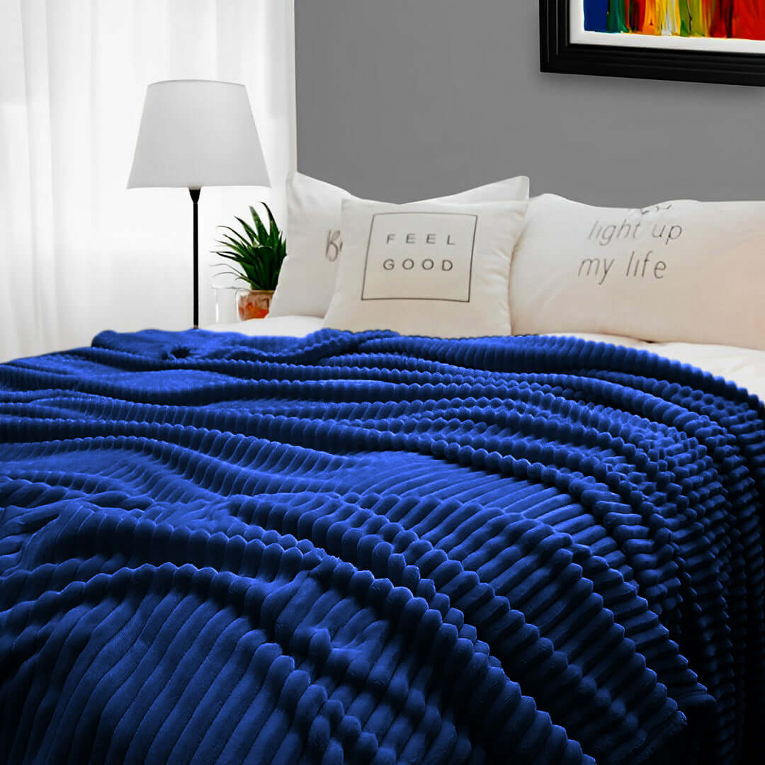 Luxurious blue ribbed blanket on bed with white pillows in a cozy, modern bedroom setting. Affordable homewares, quality, and value furniture backdrop.