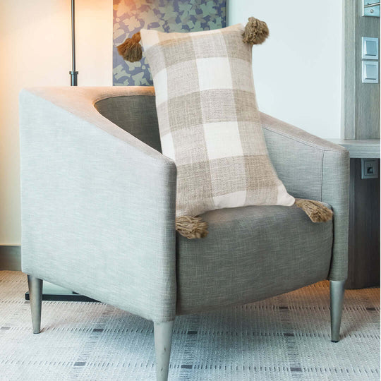 Affordable quality homewares - plaid pillow on a modern grey armchair, offering value furniture for stylish and cozy interiors.